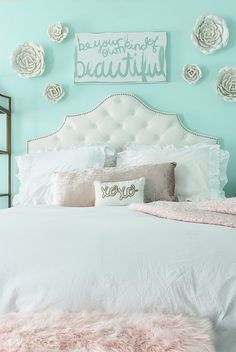 a white bed topped with lots of pillows next to a wall mounted art above it