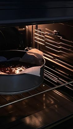 an open oven door with food cooking in the pan and light coming from inside it