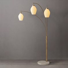 three light floor lamp with marble base and white lampshade on grey wall background