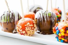 chocolate covered candies with nuts and candy toppings on a white platter, ready to be eaten