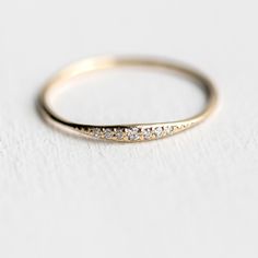 a gold wedding band with five diamonds on it's side, sitting on a white surface