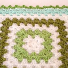 a green and white crocheted square is shown