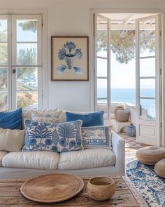 a living room filled with white furniture and lots of blue pillows on top of it