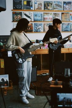 two people are playing guitars in a room