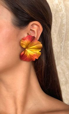 a close up of a person wearing large earrings with flowers on the back of them