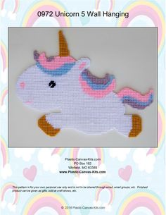 a cross stitch unicorn is hanging on a white wall with rainbows in the background