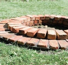 a fire pit made out of bricks in the grass