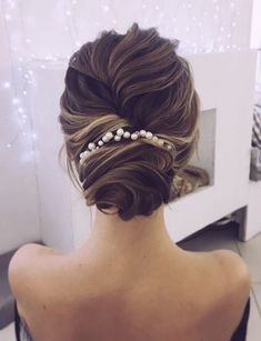 the back of a woman's head with hair in a low bun and pearls on it