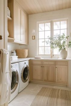 a washer and dryer in a small room with wooden cabinetry, windows, and rugs on the floor