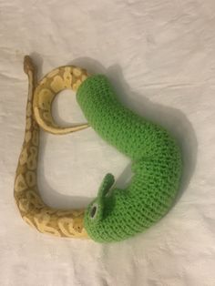 a green knitted snake on top of a white sheet