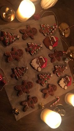 gingerbreads decorated with christmas decorations are on a piece of paper next to candles