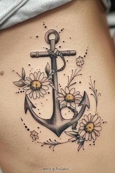 a woman's stomach with an anchor and daisies tattoo on the bottom side