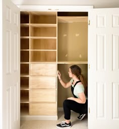 a woman kneeling down in front of a closet with drawers and shelves on both sides