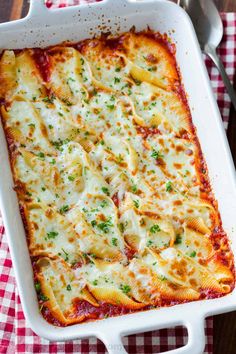 a white casserole dish filled with pasta and cheese on a checkered table cloth