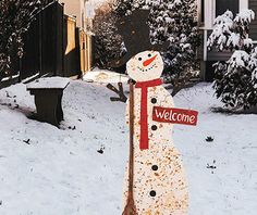 a snowman holding a welcome sign in the snow