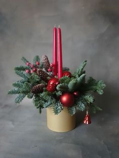 a candle holder with christmas decorations and pine cones in it on a gray background,