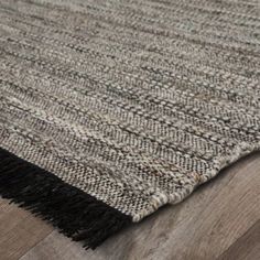 an area rug with fringes on the bottom and wood flooring in the background