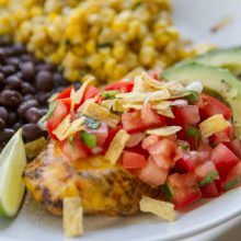 a white plate topped with black beans, corn and avocado next to other foods