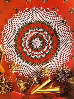 a crocheted doily with gold bells and other christmas decorations on top of it