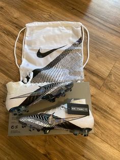 two pairs of nike soccer cleats are on the floor next to a drawstring bag