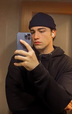 a young man taking a selfie with his cell phone in front of the mirror