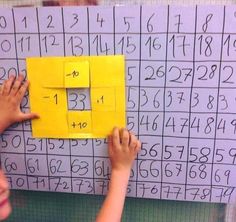 two children are playing with numbers on a sheet of paper that has been cut into squares