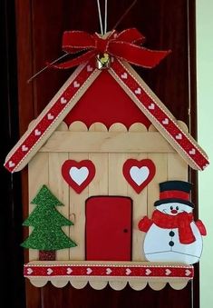 a wooden house with a snowman and christmas tree on the front door hanger