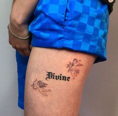 a woman with a tattoo on her thigh that reads divine and has cherubs