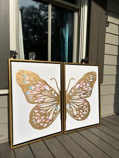 two butterfly paintings are sitting on the porch