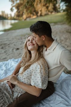 a young man and woman cuddle on the beach