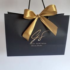 a black shopping bag with a gold bow on the front that says gf san antonio