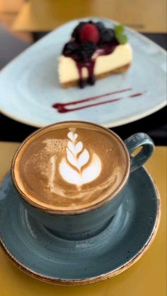 a cup of coffee with a piece of cheesecake on it sitting on a table