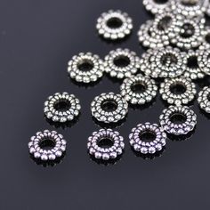 several silver colored beads on a black surface with one bead in the middle and two are