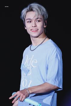 a young man with grey hair and blue shirt holding a toothbrush in his hand