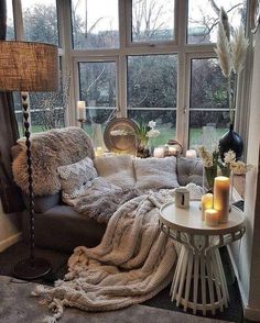 a living room filled with lots of furniture next to a large window covered in blankets