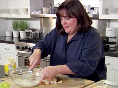 a woman in the kitchen preparing food on a cutting board with a knife and bowl