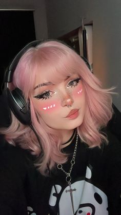 a girl with pink hair and headphones on her face is looking at the camera