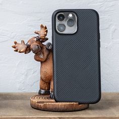 an iphone case with a moose head on it, next to a wooden stand that is made out of wood