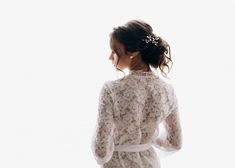 the back of a woman's head wearing a white lace robe with flowers in her hair