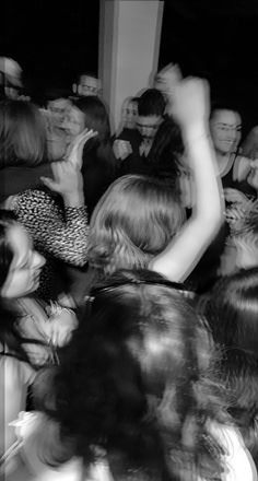 black and white photograph of people dancing at a party with their hands in the air