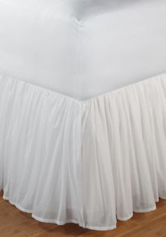 a white bed skirt on a wooden floor