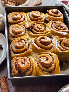 a pan filled with cinnamon rolls on top of a wooden table