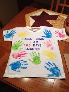 a t - shirt that says hands down and 100 days smarter on it, sitting on a wooden table