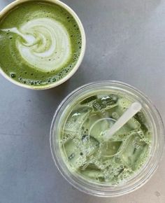 two cups filled with green liquid next to each other on top of a gray table