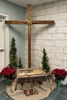 a wooden cross sitting on top of a table next to christmas trees and potted plants