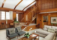 a living room filled with furniture and wooden walls