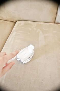 a person is cleaning a couch with a white duster on top of the couch