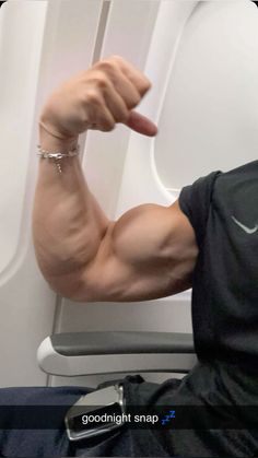 a man flexing his arm on an airplane