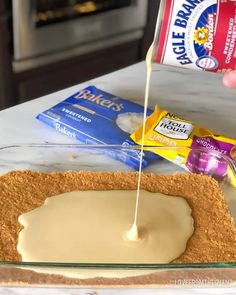 someone is spreading icing on top of a cake in a glass baking dish with graham crackers