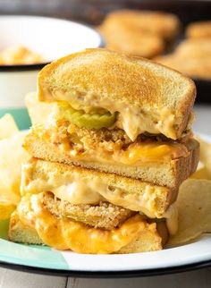 three grilled cheese sandwiches stacked on top of each other with chips in the background